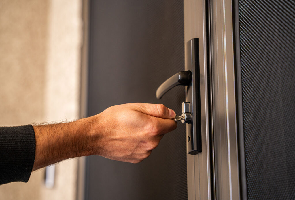 a man opening door lock made with crimsafe security screens and shield security doors